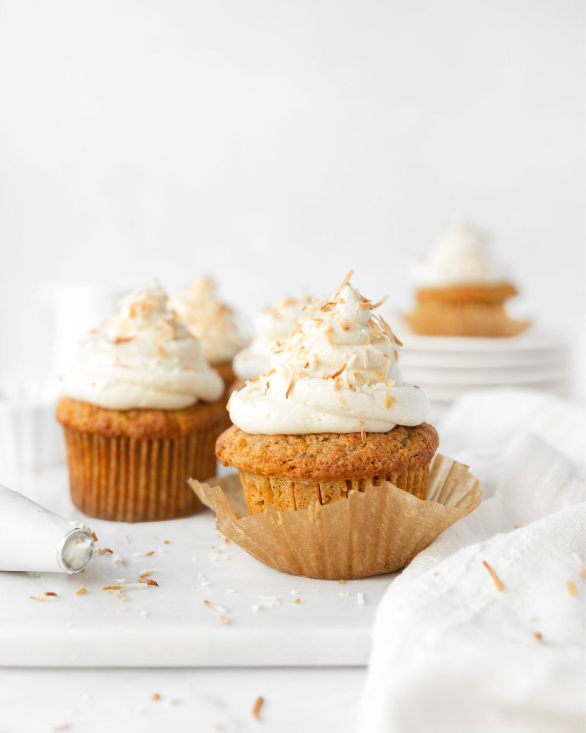 Gluten Free Carrot Cake Cupcakes with cream cheese frosting and toasted coconut on top.