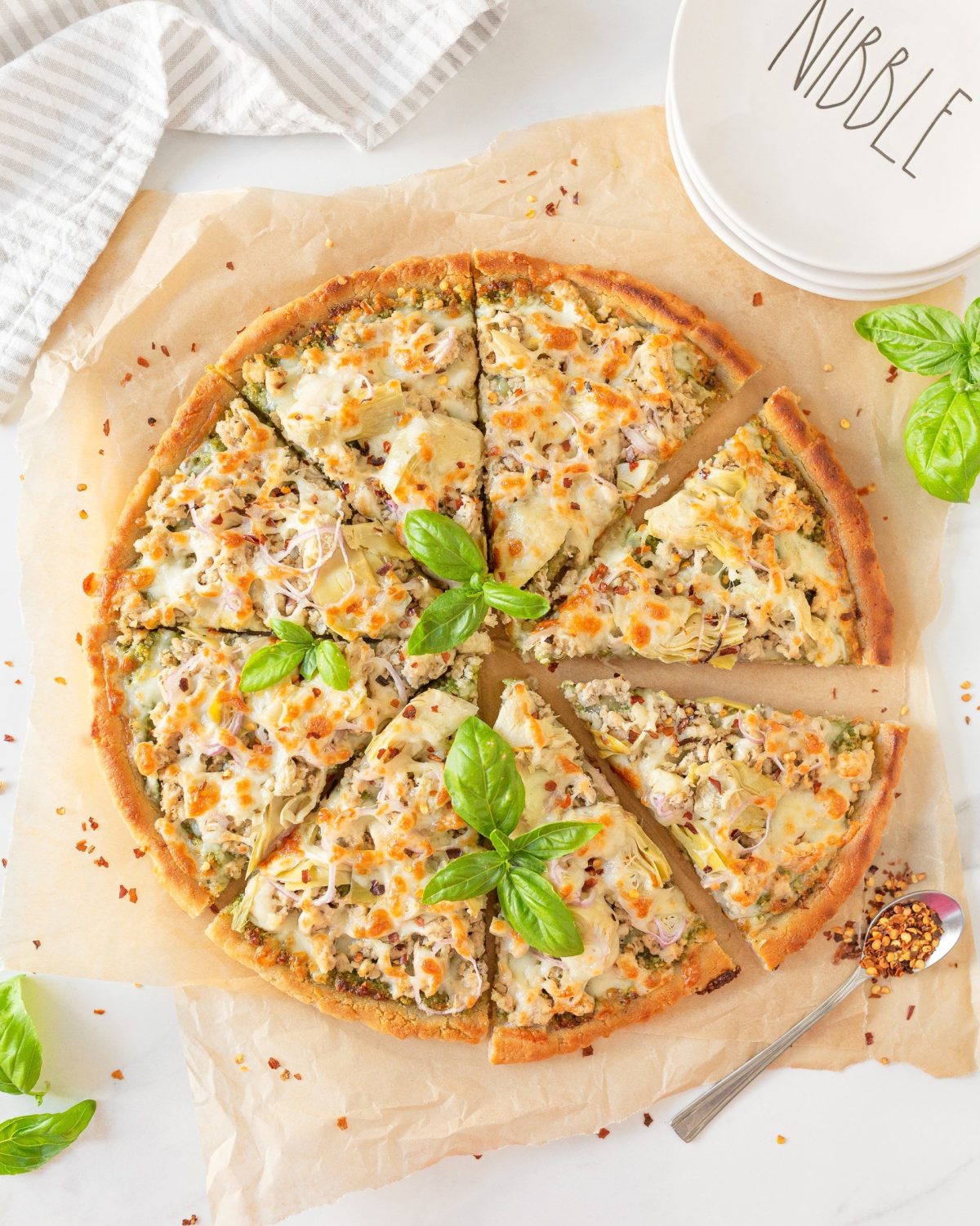 Ground Chicken Pesto Pizza cut on parchment paper.