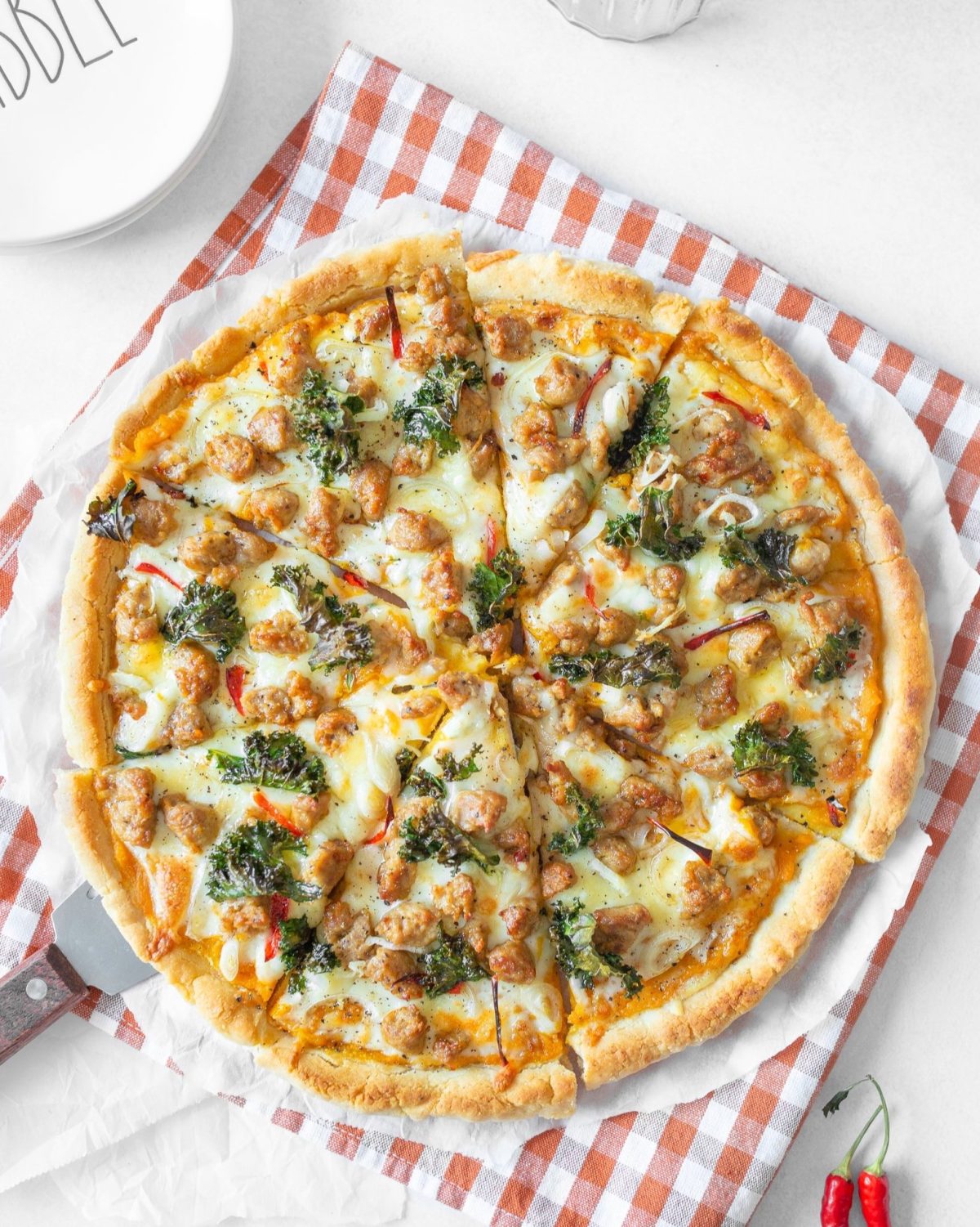 Pizza with Pumpkin, Chorizo and Kale baked and cut on parchment paper.