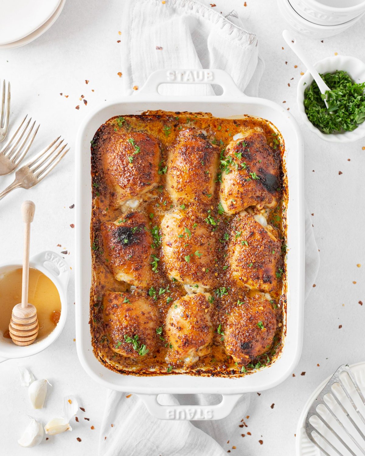 Spicy Baked Honey Mustard Chicken Thighs baked in a dish and topped with fresh parsley.