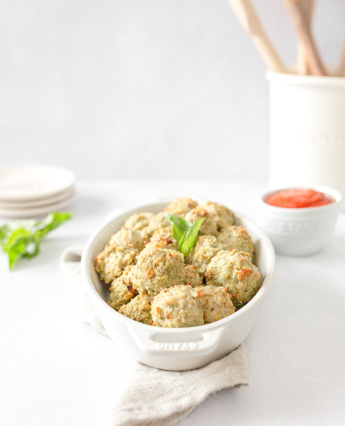 Gluten Free Pesto Chicken Meatballs cooked in a dish and topped with fresh basil.