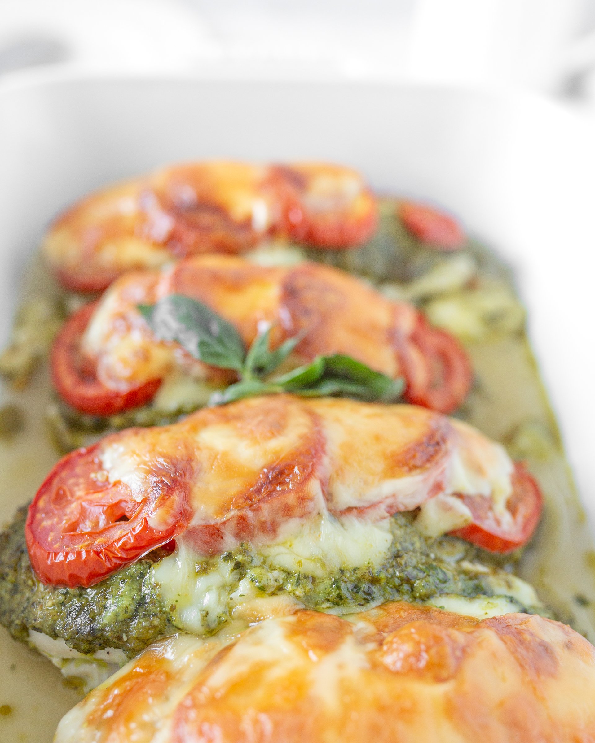 5-Ingredient Pesto Baked Chicken cooked in a dish and garnished with fresh basil.
