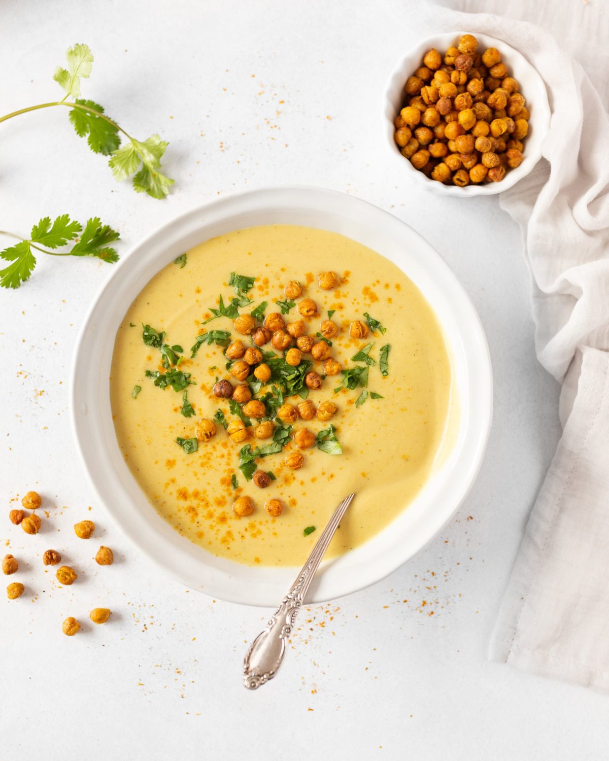 Vegan Curried Cauliflower Soup with served in a bowl and garnished with fresh cilantro and crispy roasted chickpeas.