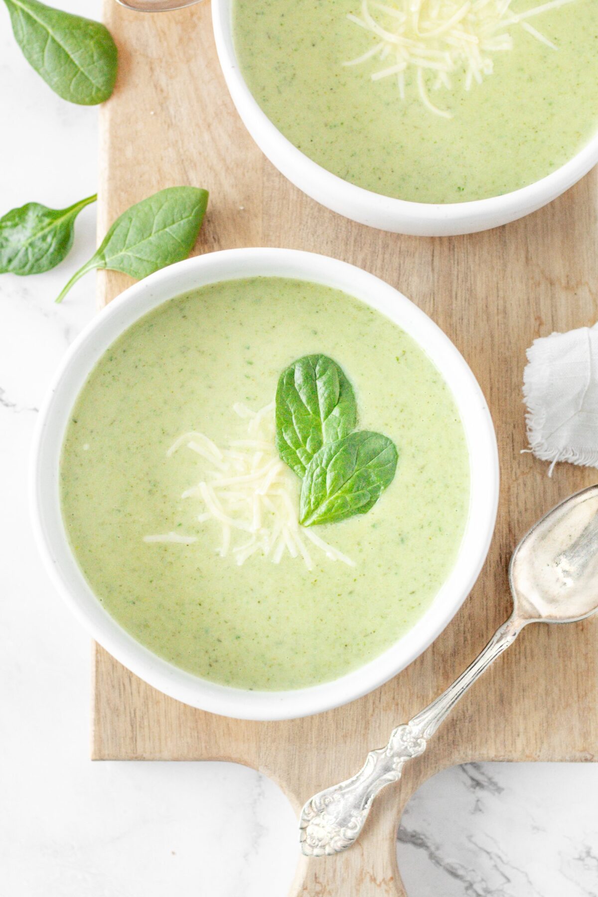 Green Goddess Soup in a bowl, topped with shredded parmigiana cheese and fresh basil.