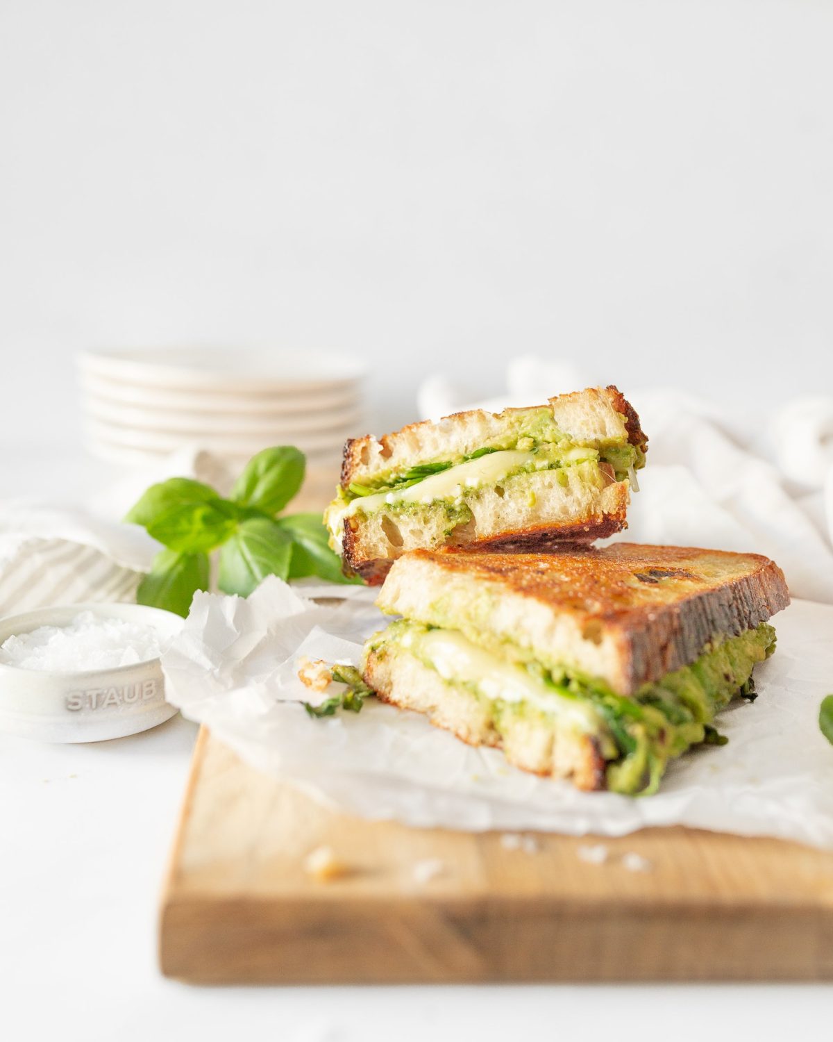 Grilled sandwich cut in half on parchment paper.