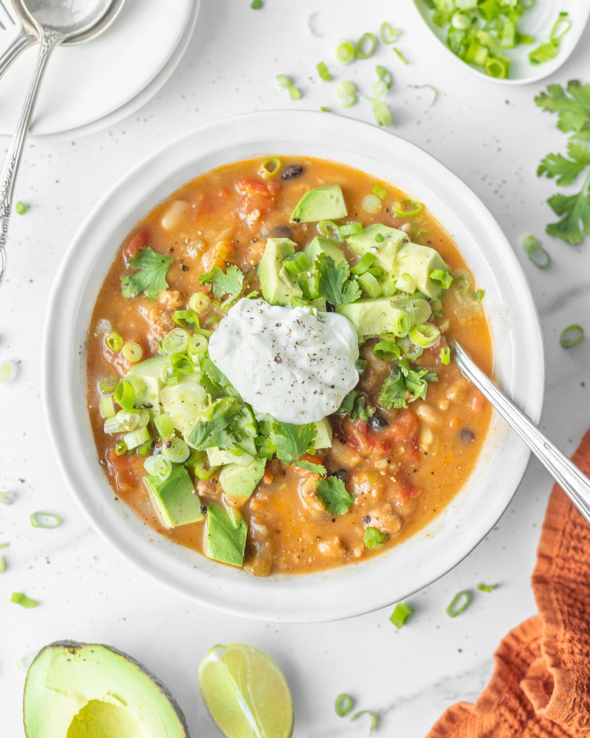 Turkey and Acorn Squash Chilli served in a bowl and topped with avocado, green onion and sour cream.