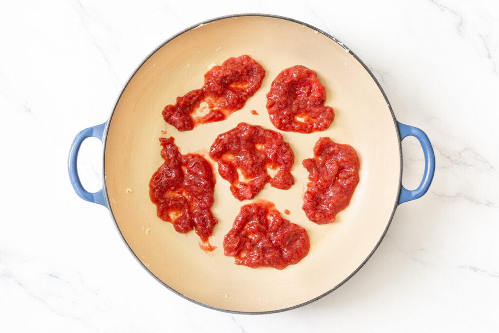Process shot #4: Half of the strawberry rhubarb compote added to the bottom of the prepared baking dish/pan. It is partially spread around, but not fully covering the bottom of the pan. 