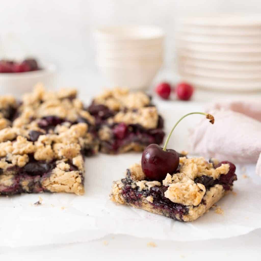 Gluten-free Cherry Crumble Bars baked and cut on parchment paper.