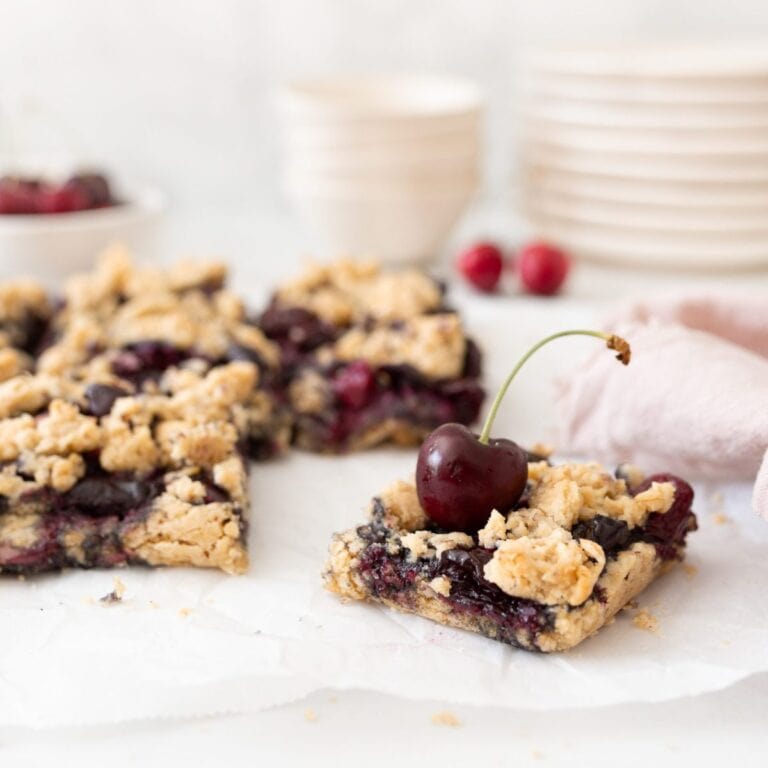 Gluten-free Cherry Crumble Bars baked and cut on parchment paper.