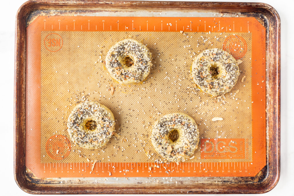 Process shot #5: Greek Yogurt Bagels formed, brushed with egg wash and sprinkled with everything bagel seasoning on a silicone matt lined baking sheet.