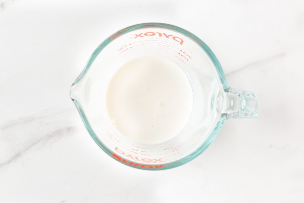Process shot #1: Homemade buttermilk in a small glass measuring cup. 