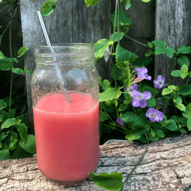 a guava juice sitting outside in front of flowers