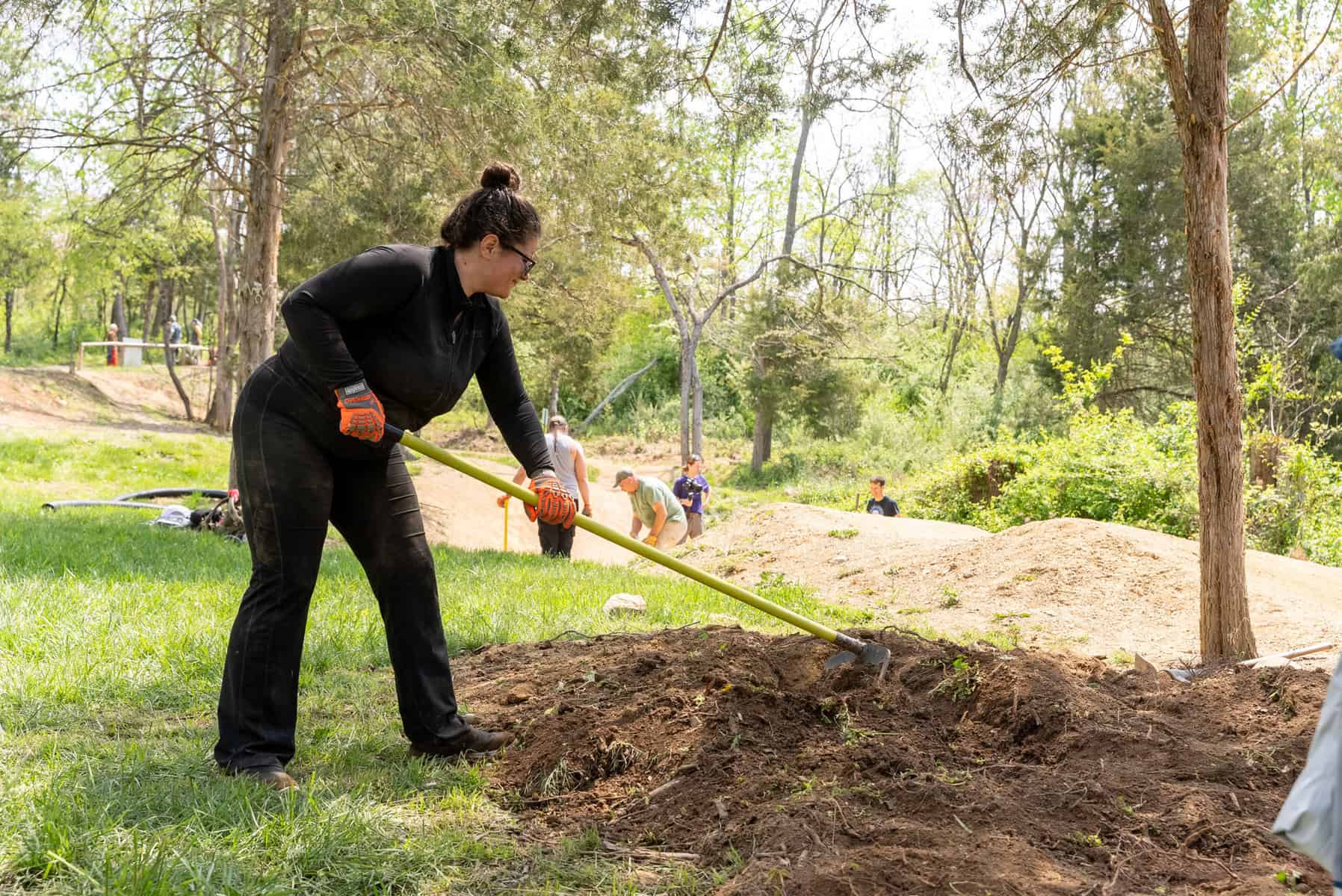 A volunteer shaping new trail with a rake at a Dig Day