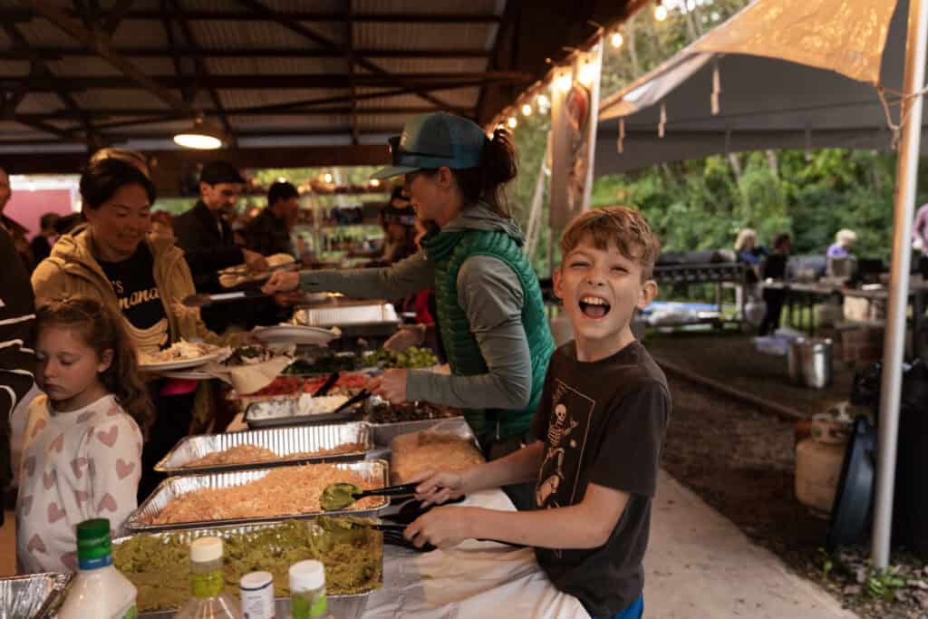 People serving food at outdoor gathering.