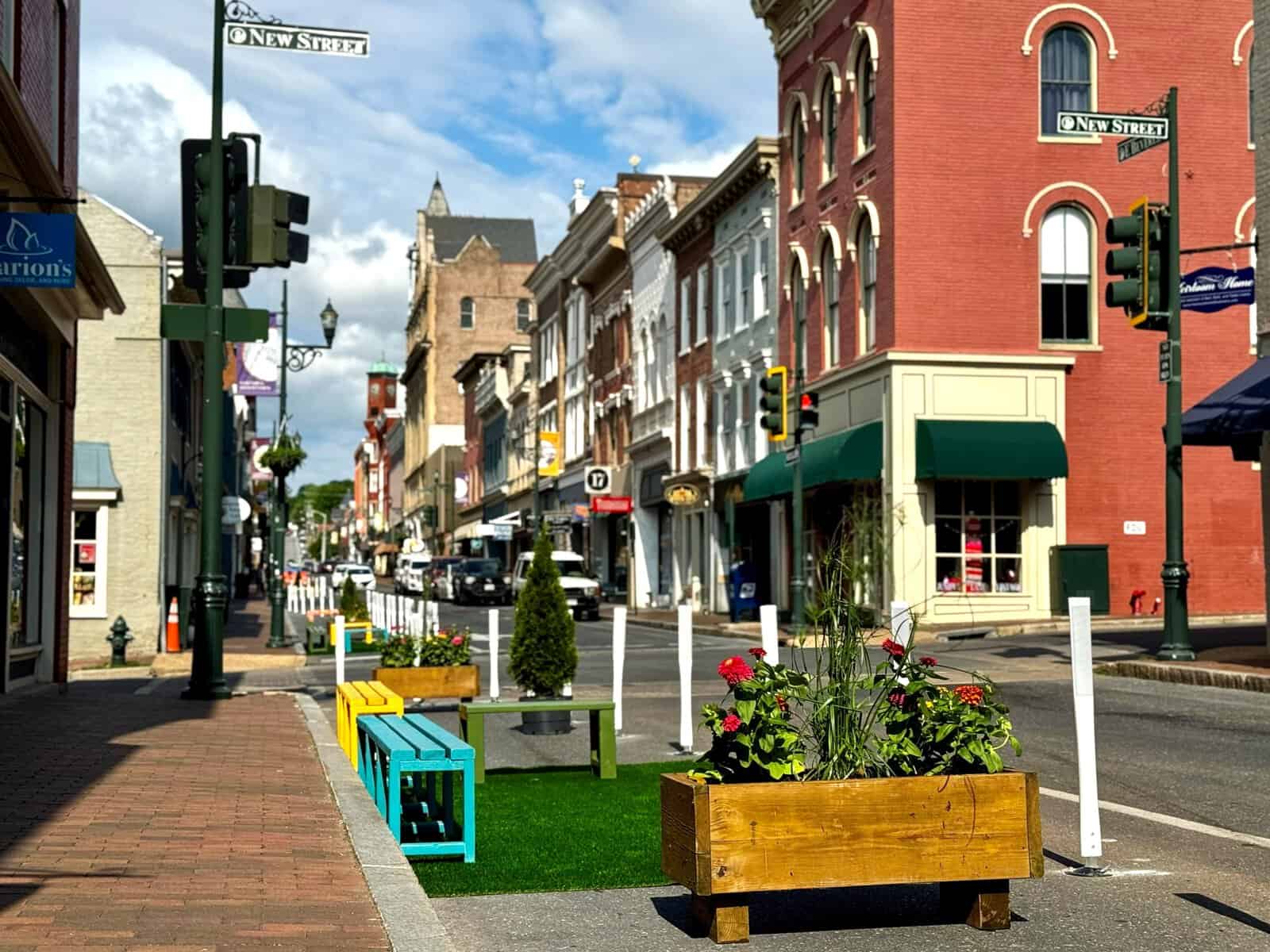 Colorful benches, a flower planter box, and a patch of turf behind white flexible posts on Beverley Street at New Street in downtown Staunton during the June 2026 demonstration project