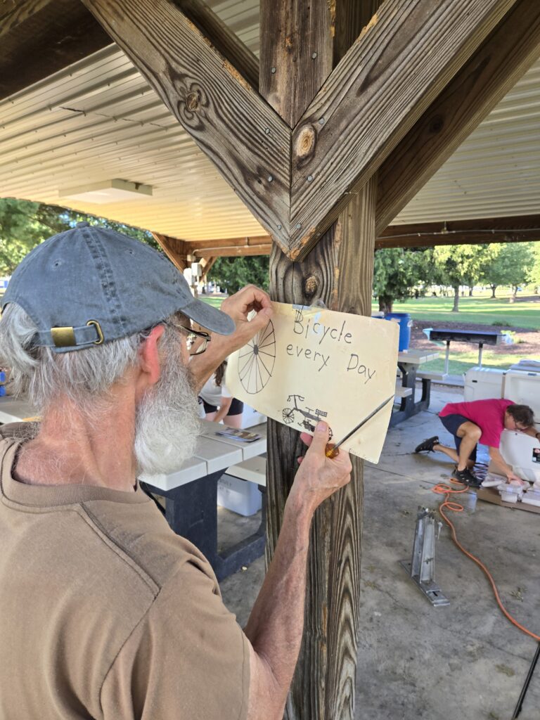 Art hanging up his son's kindergarten drawing, titled Bicycle Every Day, at the Century 2026 Century Recap: Shenandoah Pixie Dust in Action