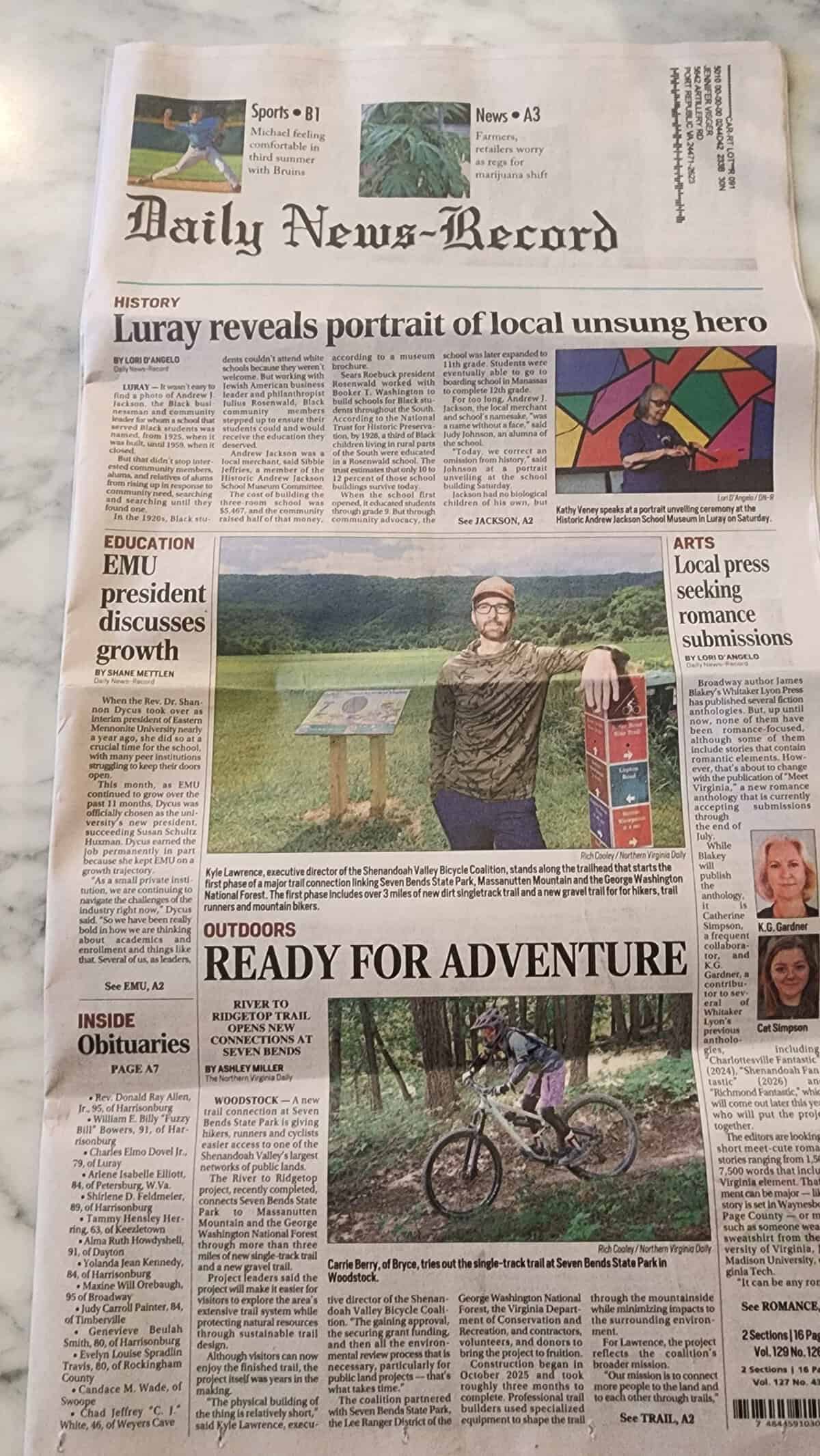 Front page of the Daily News-Record with the headline "Ready for Adventure," featuring a photo of Kyle Lawrence beside a trail sign at Seven Bends State Park and a mountain biker riding the new singletrack.