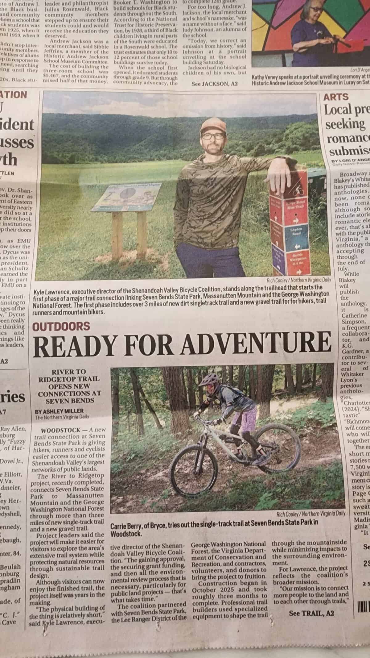 Close-up of the Daily News-Record story "Ready for Adventure," showing Kyle Lawrence at a Seven Bends State Park trail sign and a mountain biker on the new River to Ridgetop singletrack.