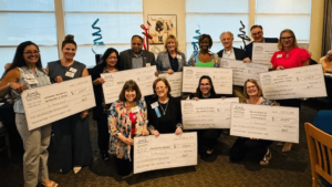 10 non profit organization leaders holding donation checks.