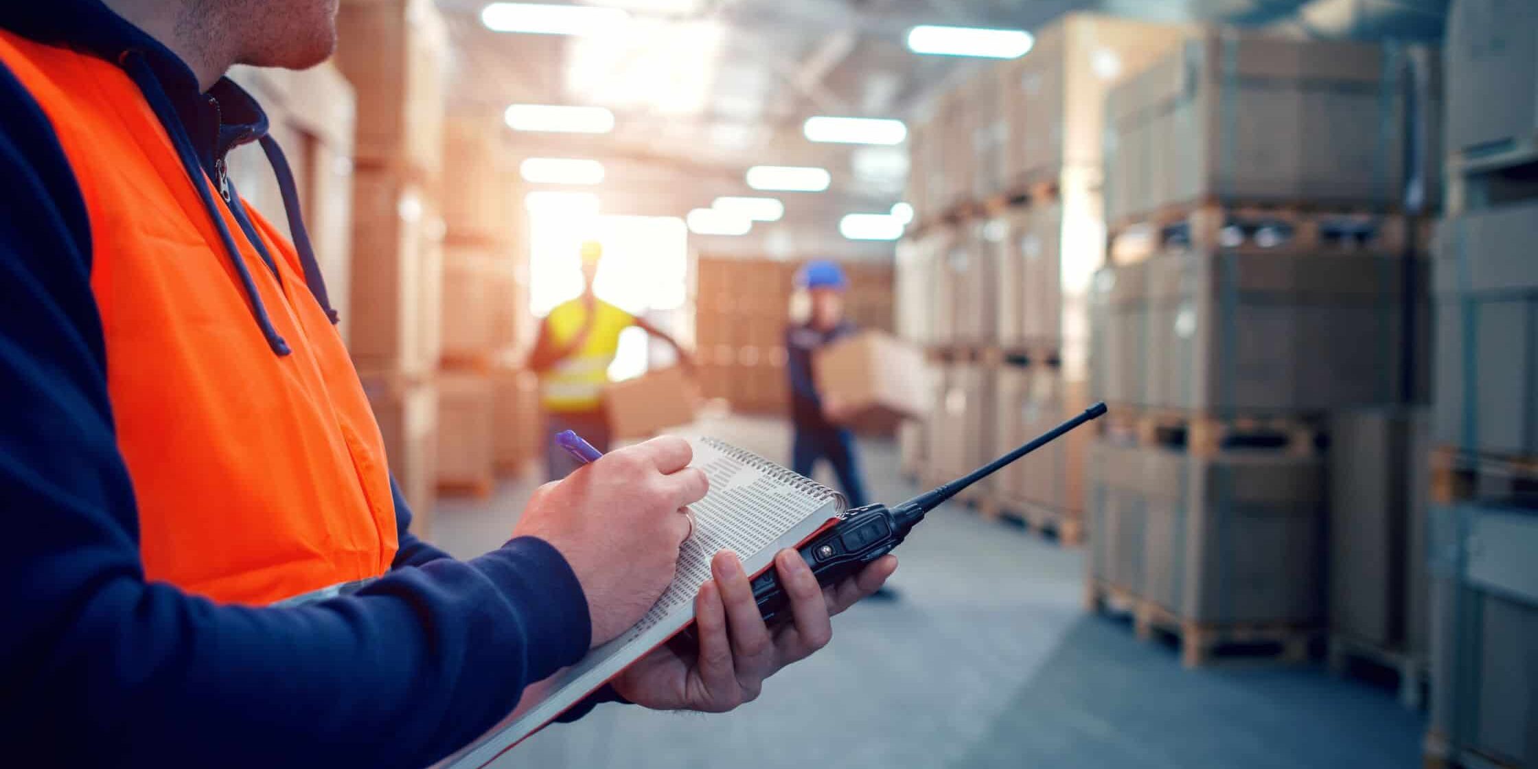 Worker with clipboard in warehouse for safety check