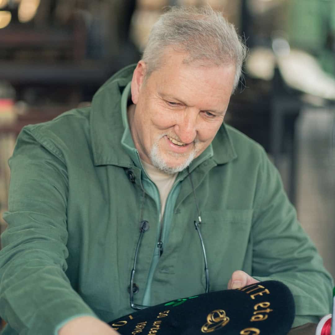 Luis limpiando hilos de una txapela personalizada en el taller