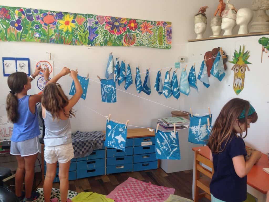 Colorful youth art project with children hanging blue and white paper crafts.