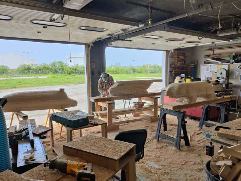 Wooden boat being shaped in a bright, spacious workshop.