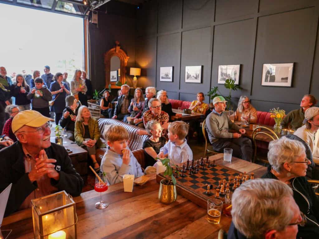 Attendees enjoying a chess game at Catalyst 2024 event in a cozy, well-lit venue.