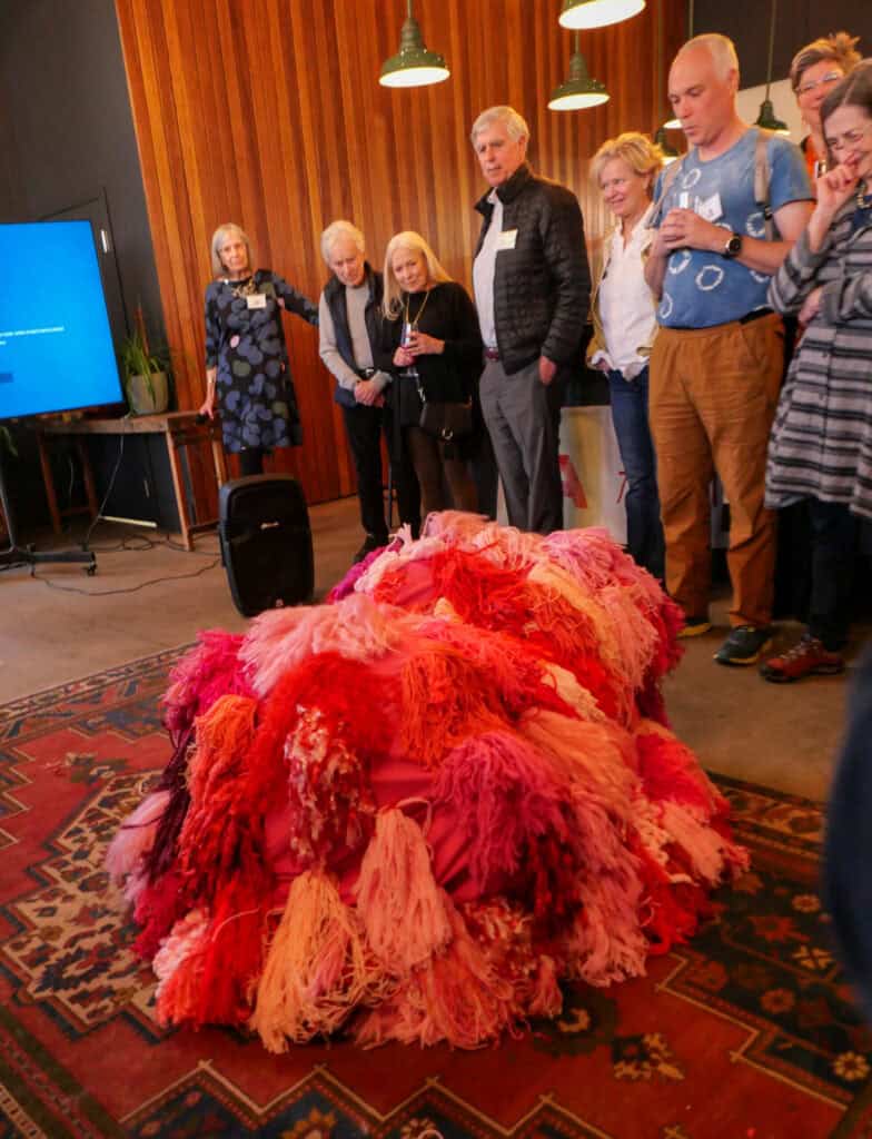 Colorful textile art piece with pink, red, and orange fibers at Catalyst 2024 gathering.