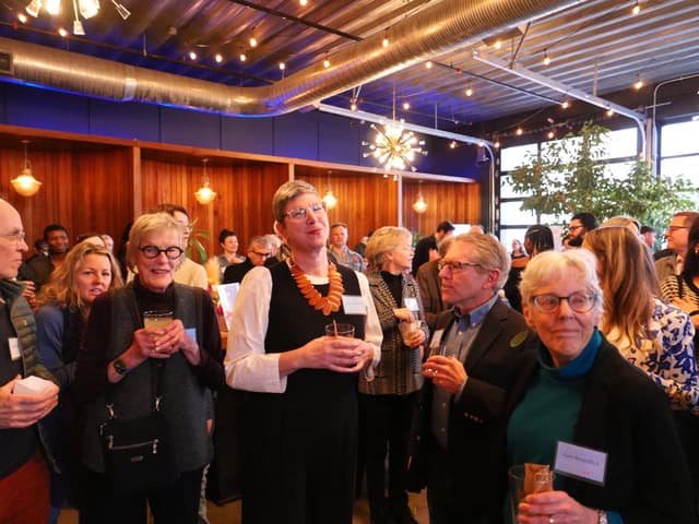 Group of diverse people enjoying art event in a contemporary gallery setting.