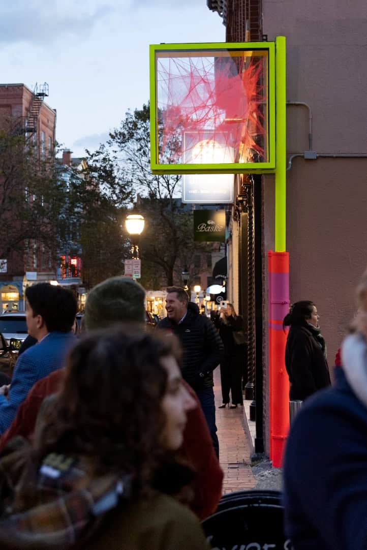 Colorful digital art installation on city street storefront.