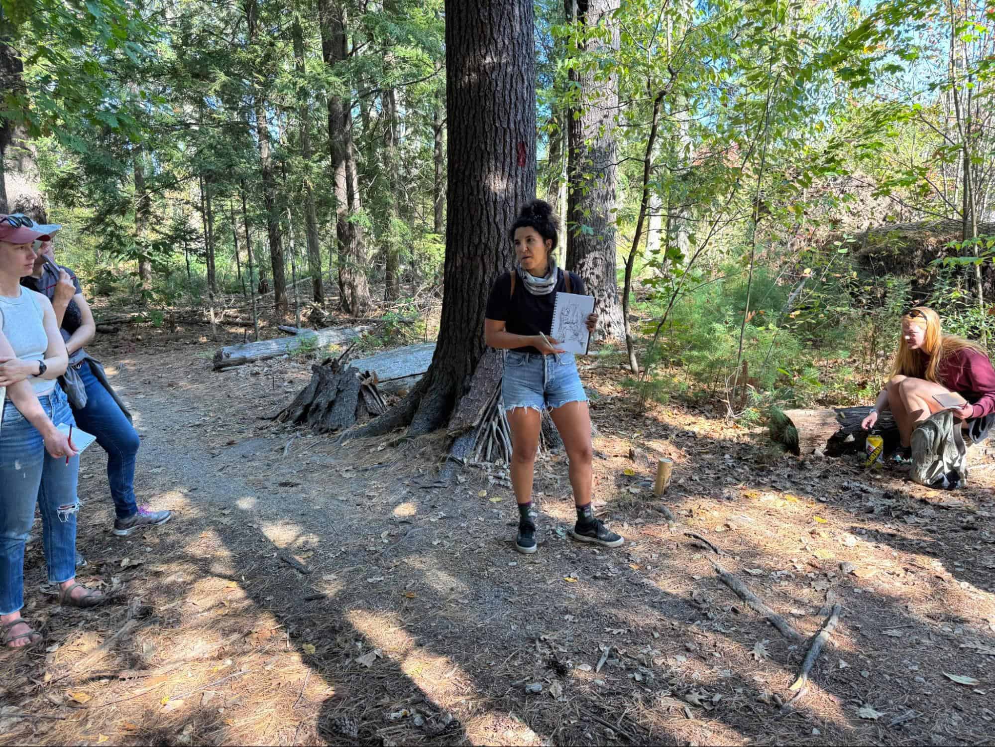 Outdoor art class in a lush forest setting with children and instructor.