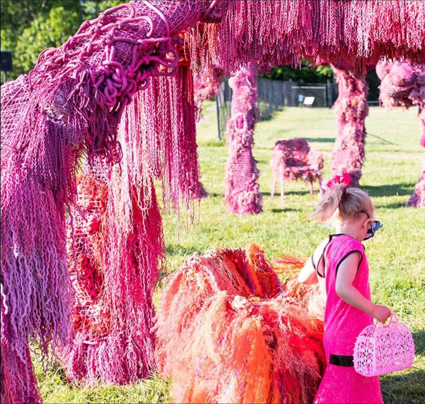 Colorful yarn art installation with pink trees and sculptures.