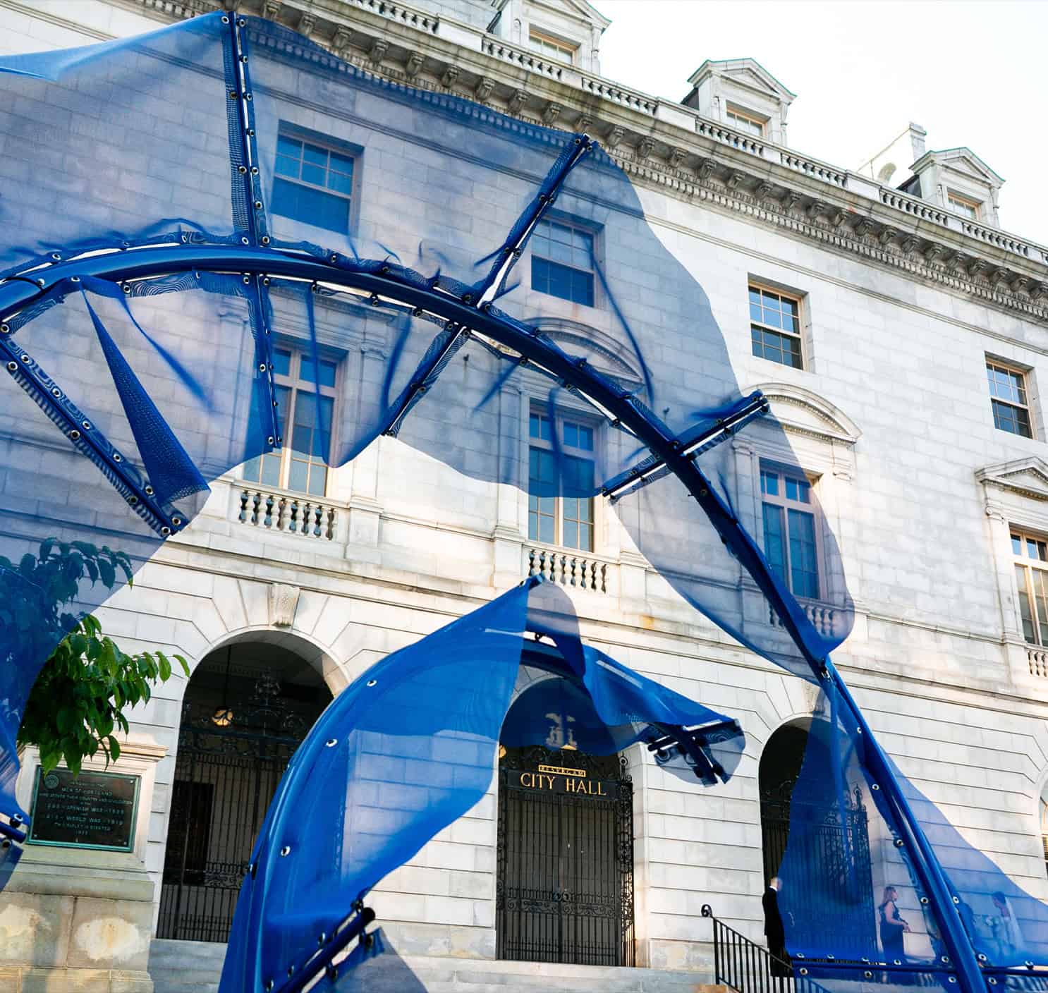 Modern blue art installation on City Hall building facade in an urban setting.