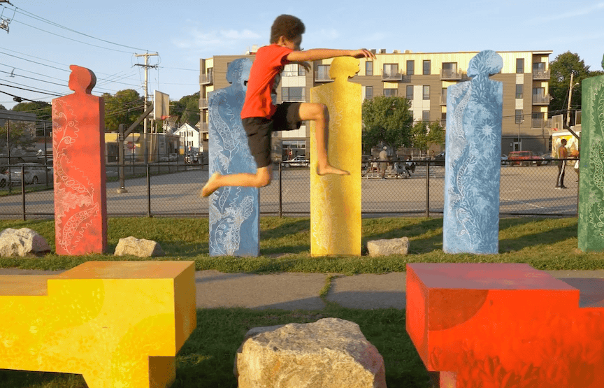 Colorful human-shaped sculptures in an outdoor park art installation, featuring bright hues and play.