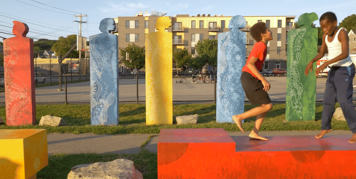 Vibrant outdoor art installation with children playing among colorful sculptures.