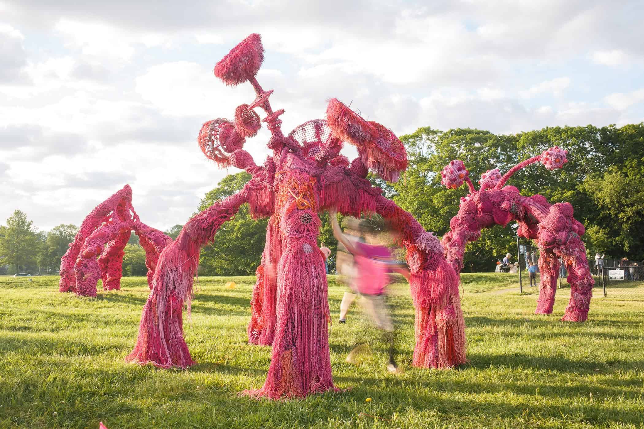 An imaginative pink tree sculpture with flowing textures in a lush outdoor setting.