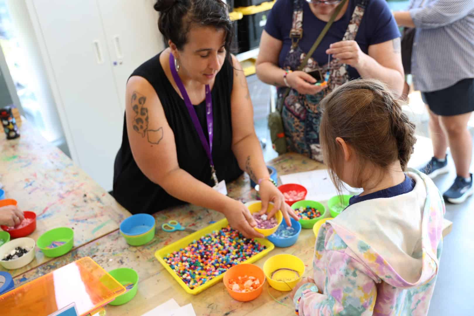 Artist and child creating bead art at TEMPOart event in Maine.