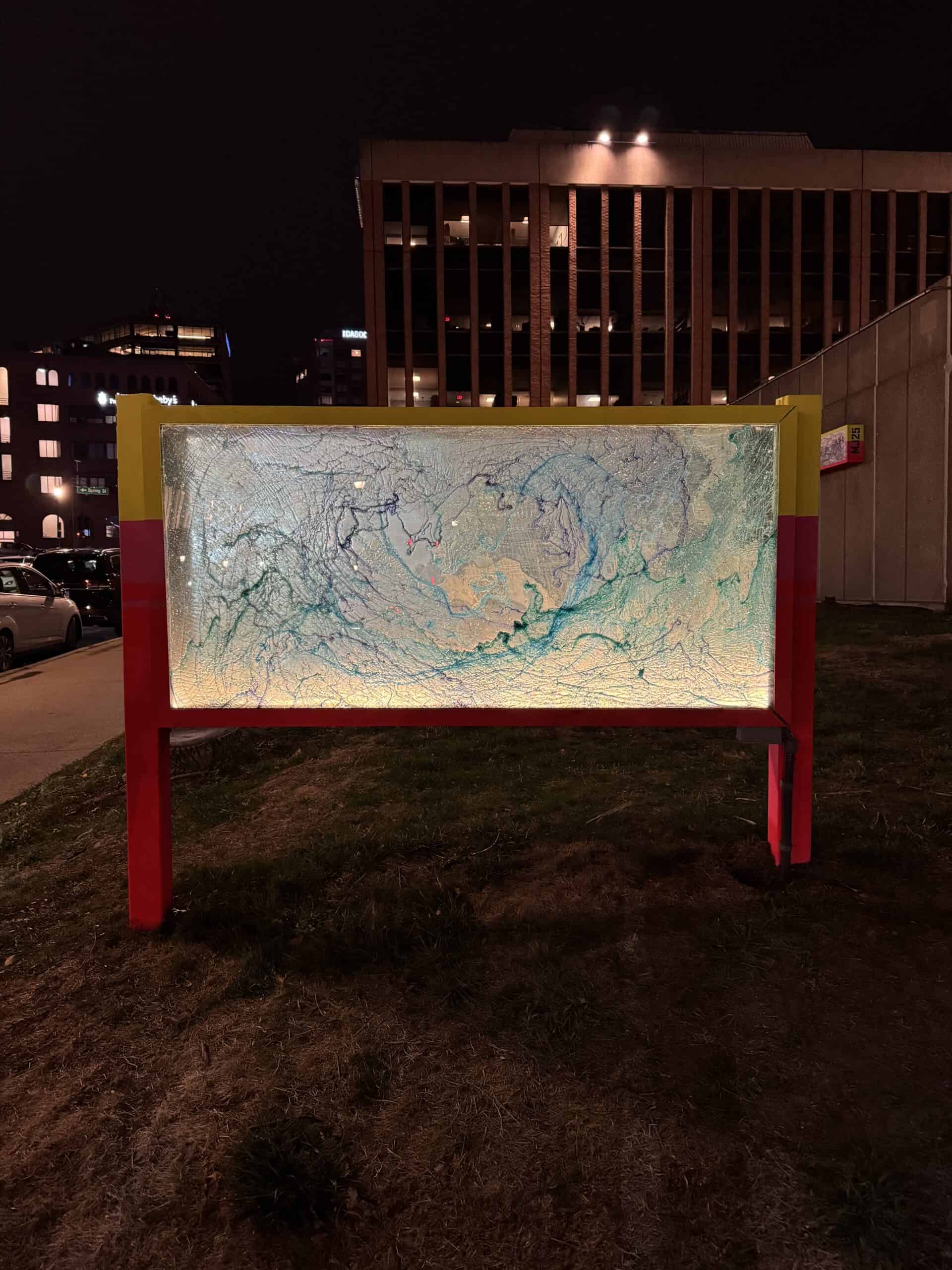 Colorful illuminated art display outdoors at night in an urban setting.