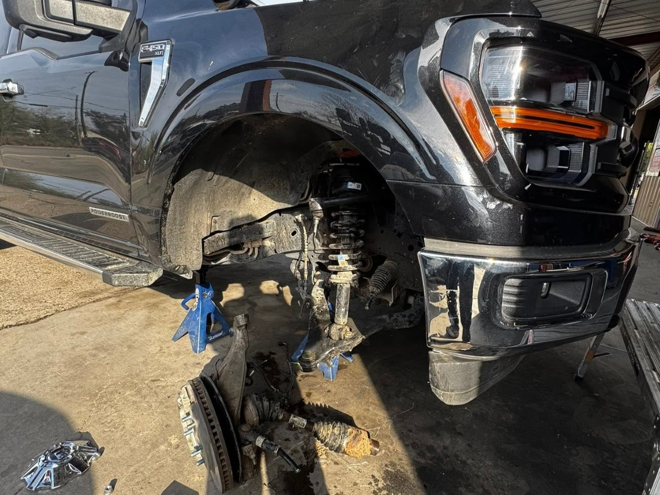 Black pickup truck with front wheel removed at Texas Automotive & Tire LLC.