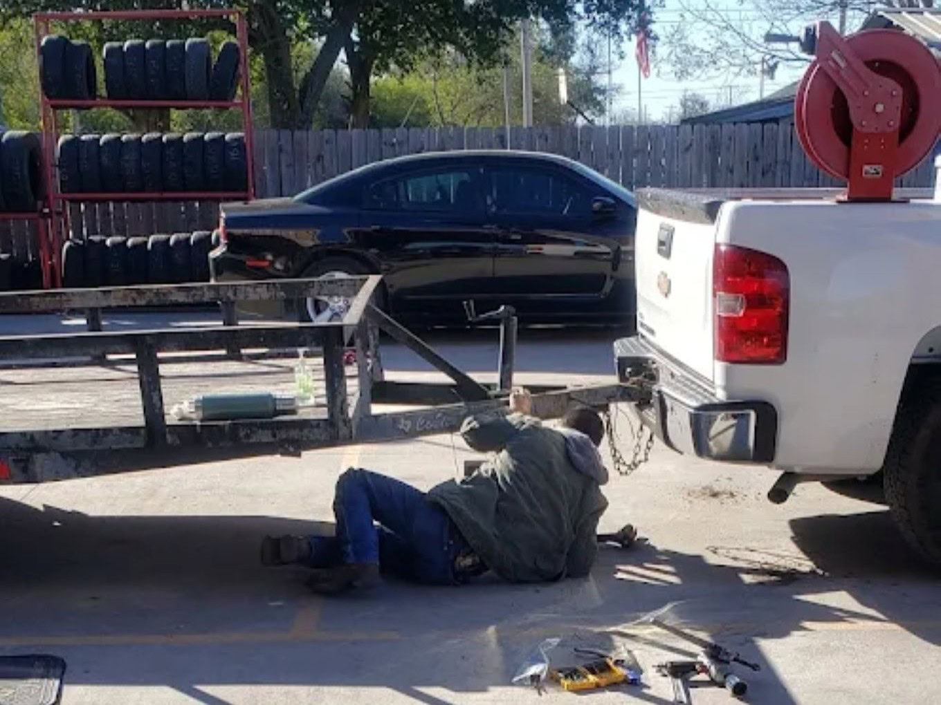 Technician repairing a vehicle under a pickup truck at Texas Tire LLC.