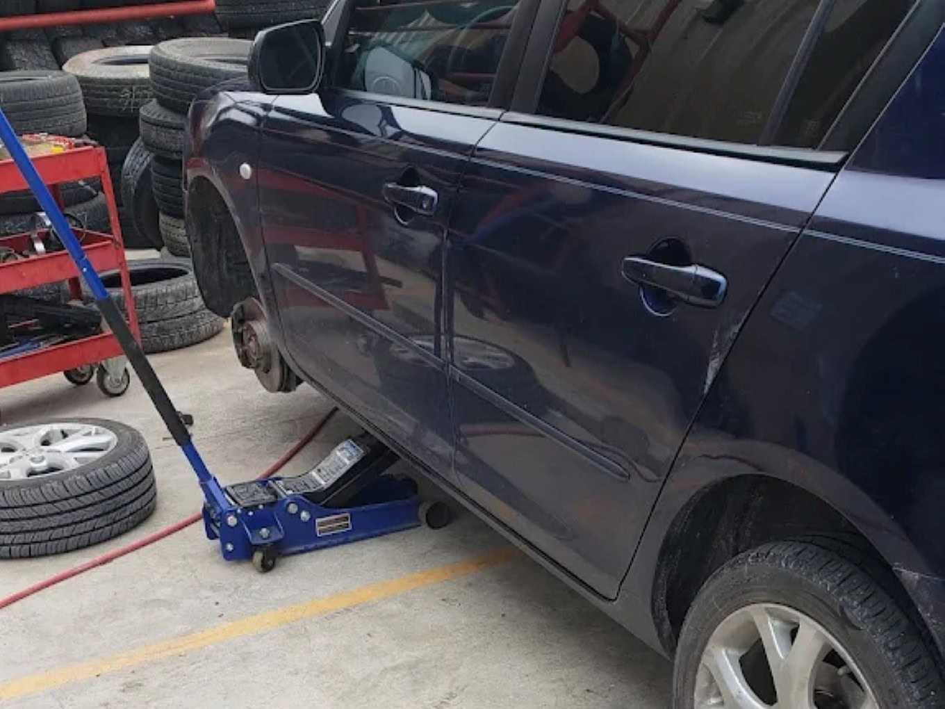 Car on hydraulic lift with tire removed at Texas Automotive & Tire LLC.