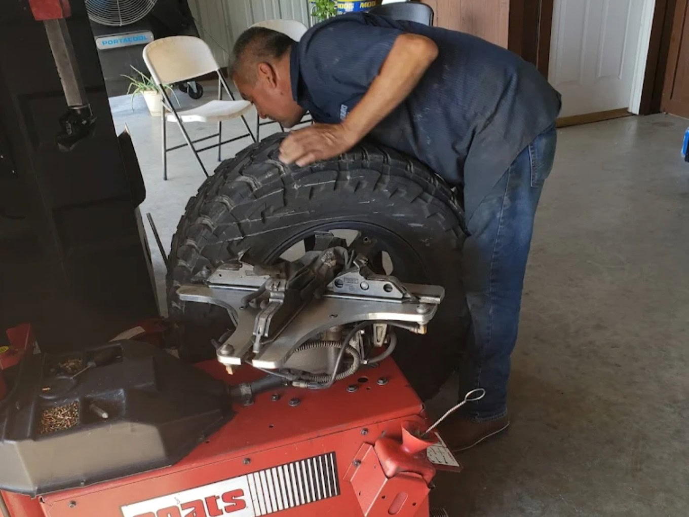 Technician repairing a large tire on a specialized machine at Texas Tire LLC.
