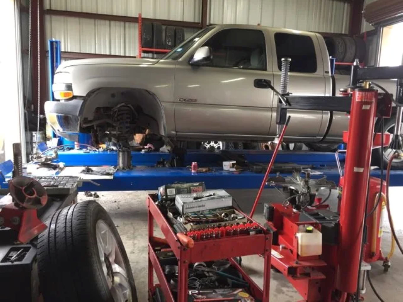 Silver pickup truck on lift at Texas Automotive & Tire LLC.