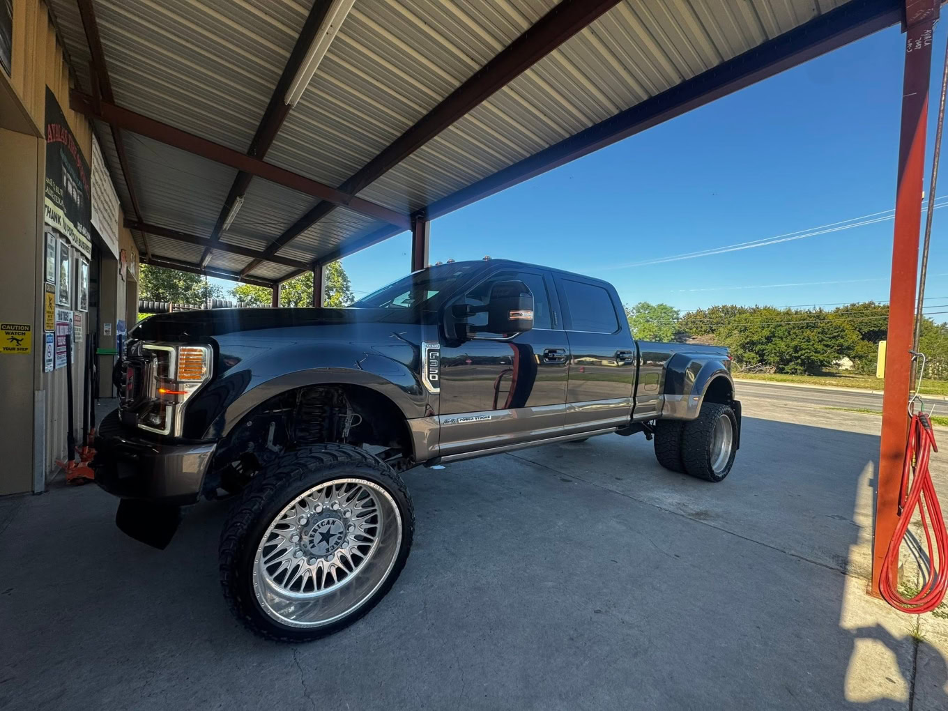Large black pickup truck with custom wheels at Texas Tire LLC in Texas.