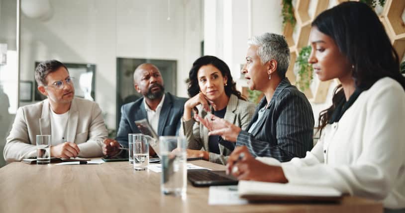 Board members in discussion during a nonprofit executive search committee meeting around a conference table.