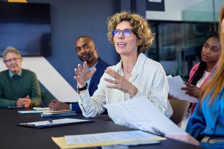 Professional woman presenting to a group during a nonprofit executive search committee meeting