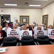 Protesters holding signs against the data center development in Fostoria, emphasizing preserving rural community identity.