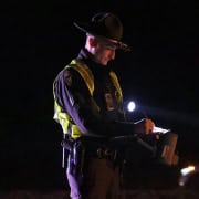 Police officer writing reports during night patrol.