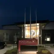 Fostoria Free Press building at night with illuminated sign and logo.